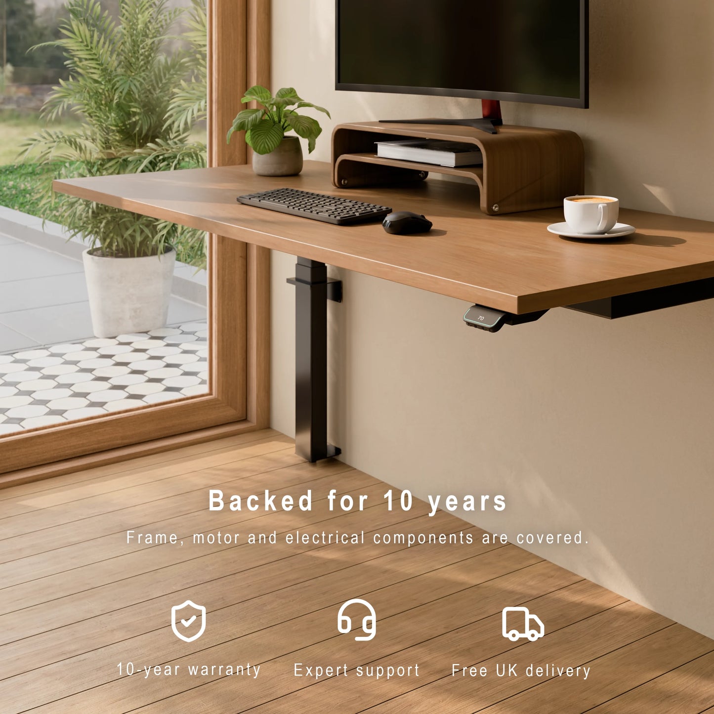 Wall-mounted LINAK height adjustable desk with 10-year warranty, expert support and free UK delivery. Wooden desk with computer setup in a room with a window view, featuring a 10-year warranty text.