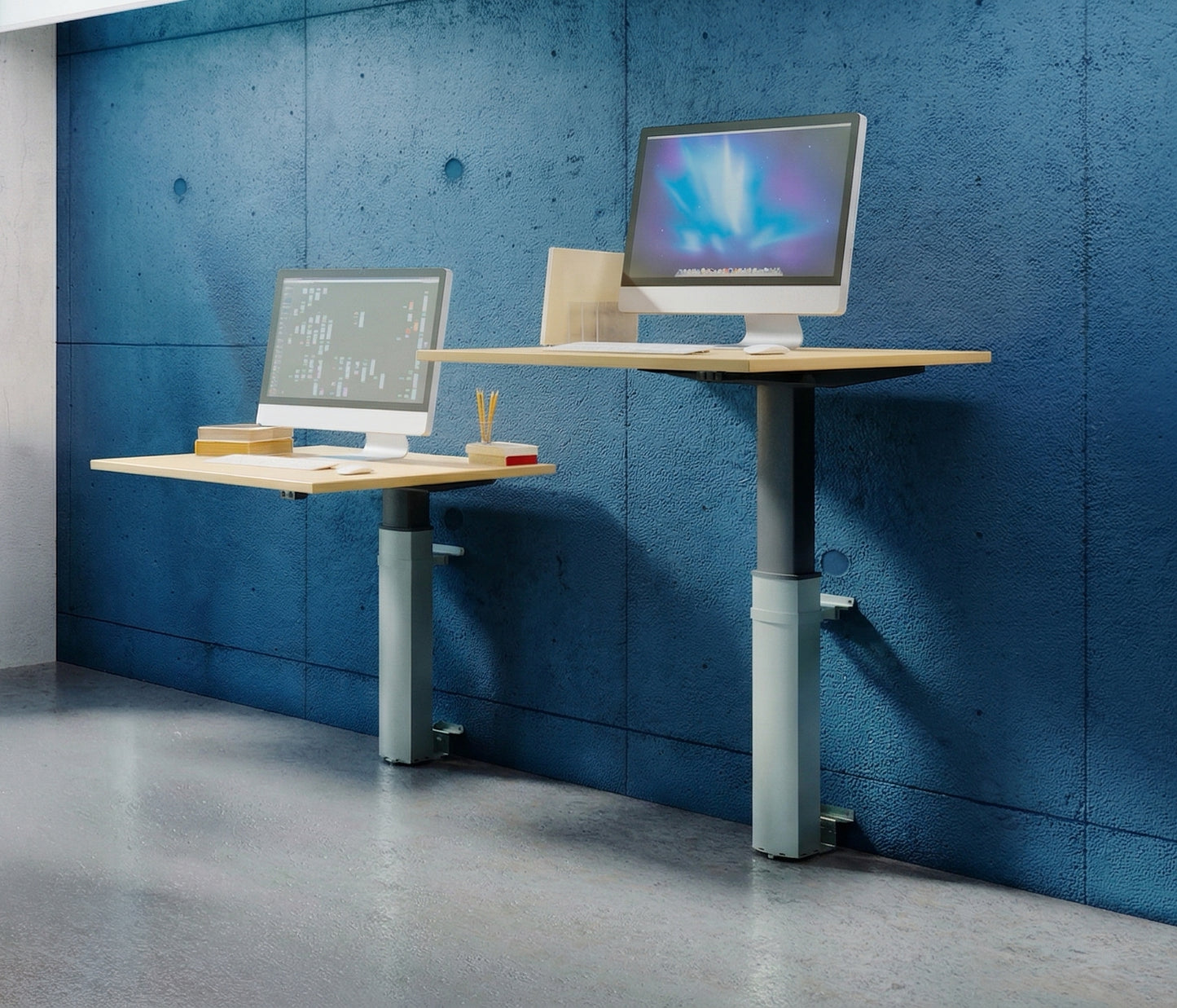 Two ConSet 501-19 wall-mounted desks shown at different heights against a textured blue concrete-style wall. One desk is at a sitting height and the other is at a standing height, each supporting a silver desktop computer. The desks feature light wood tops and silver-grey adjustable lifting columns, demonstrating the range of motion and space-saving design in a modern, industrial office setting.