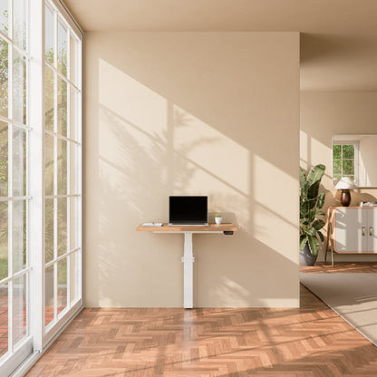 Linak Wall Solo adjustable desk with wood desktop and laptop in a bright home office