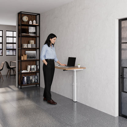 Person using the Linak Wall Solo adjustable desk with laptop in a modern office setting