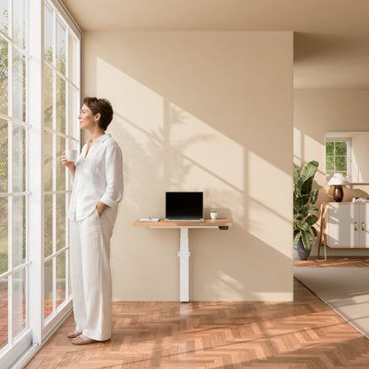 Person standing beside the Linak Wall Solo adjustable desk in a bright home office